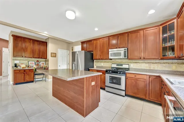a kitchen with stainless steel appliances granite countertop a stove top oven a refrigerator a sink and dishwasher