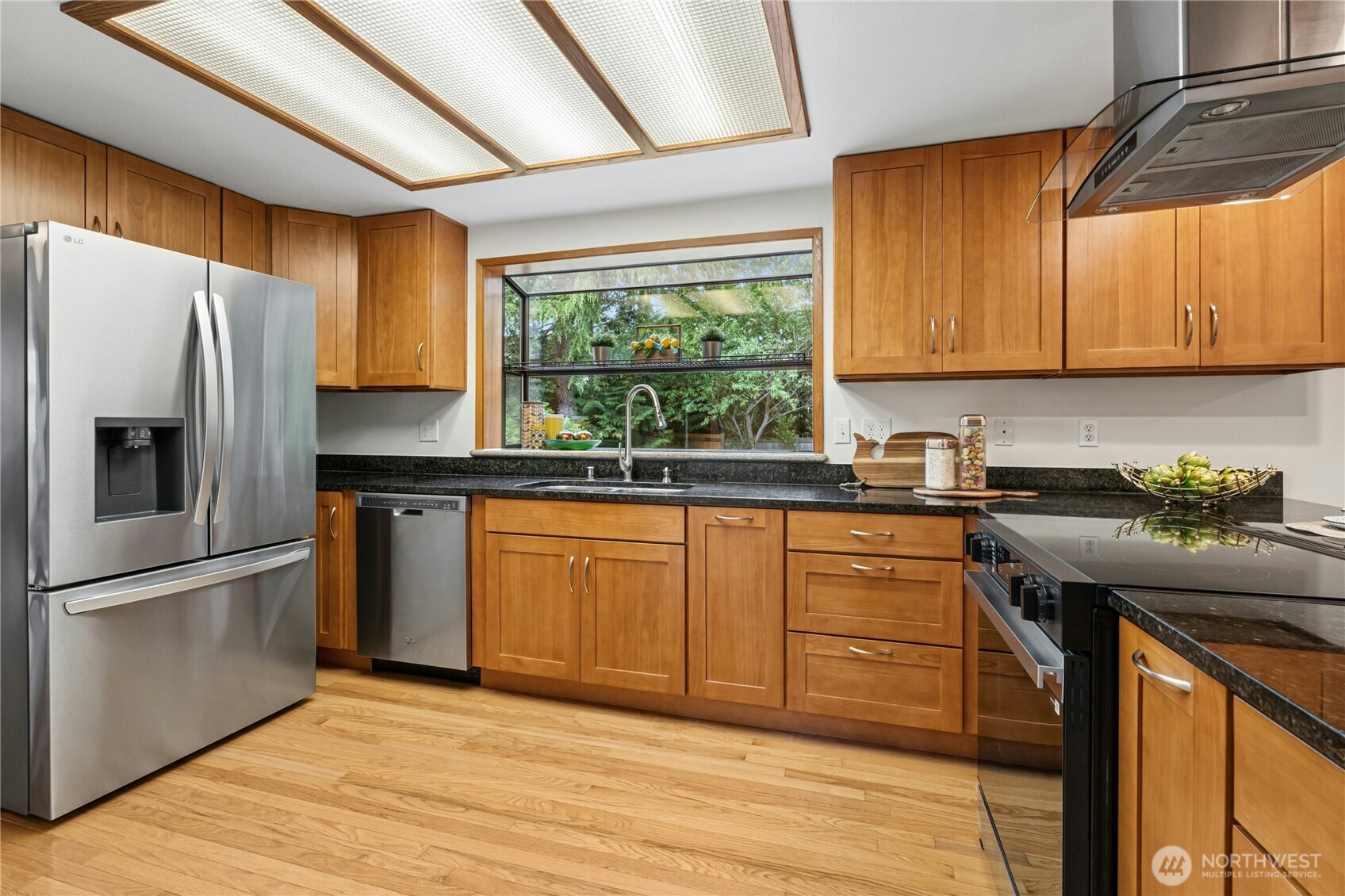 5211 103rd Street Southwest, Unit SW Mukilteo, WA 98275 - Photo 12 of 40 a kitchen with stainless steel appliances granite countertop a refrigerator a sink dishwasher a stove and white countertops with wooden floor