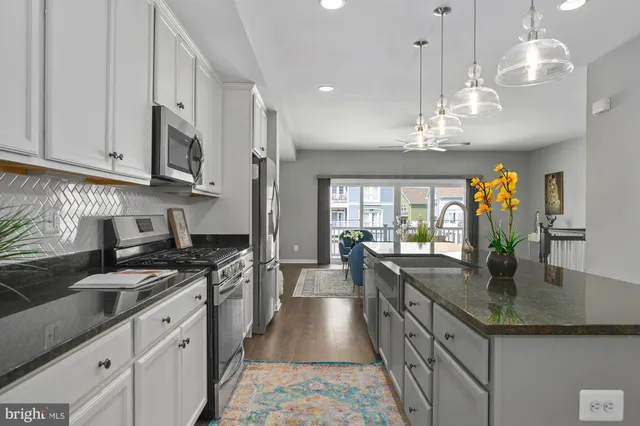 a kitchen with stainless steel appliances granite countertop a sink a stove and a wooden floors