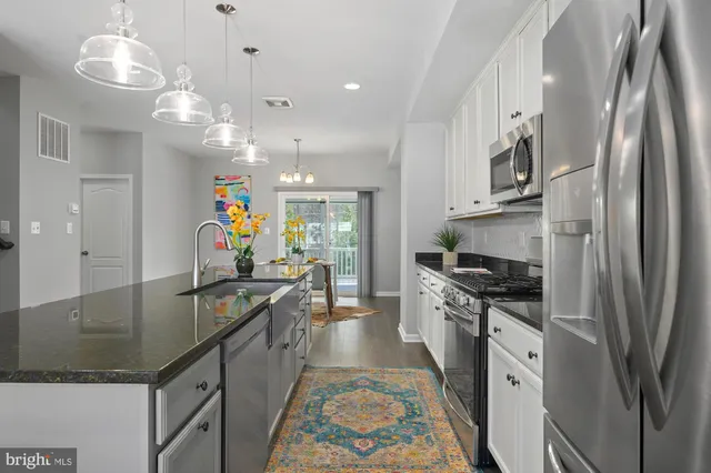 a kitchen with stainless steel appliances granite countertop a refrigerator a stove top oven a sink dishwasher and a refrigerator with wooden floor