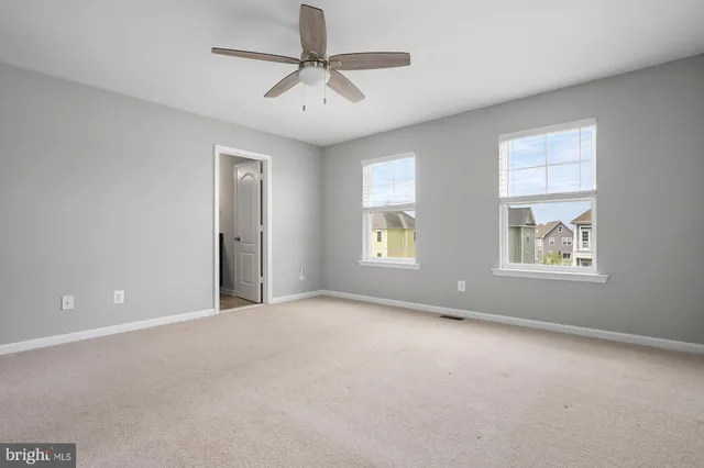 an empty room with closet and a ceiling fan
