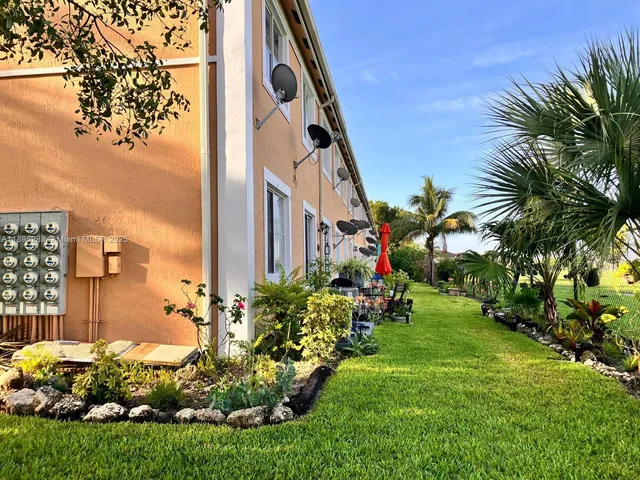 a view of a backyard with plants and palm trees