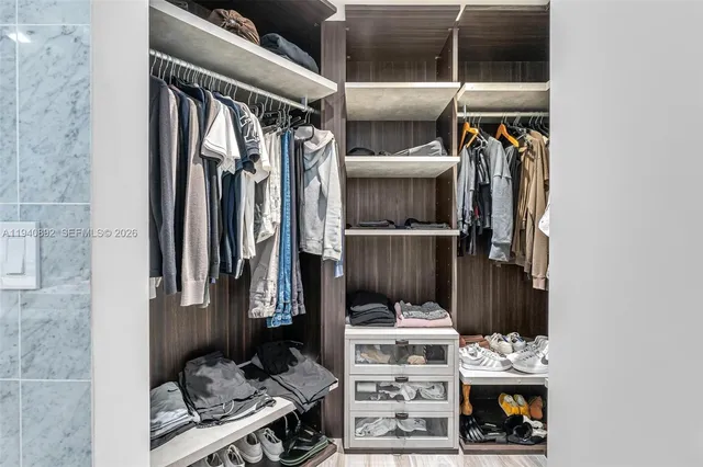 a view of walk in closet with clothes and shoes