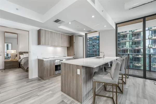 a kitchen with stainless steel appliances granite countertop a stove top oven a sink dishwasher a dining table and chairs with wooden floor