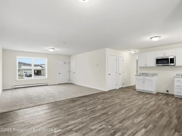 an empty room with kitchen view and windows