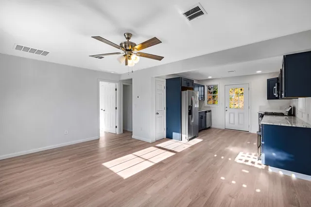 a view of an empty room with window and wooden floor
