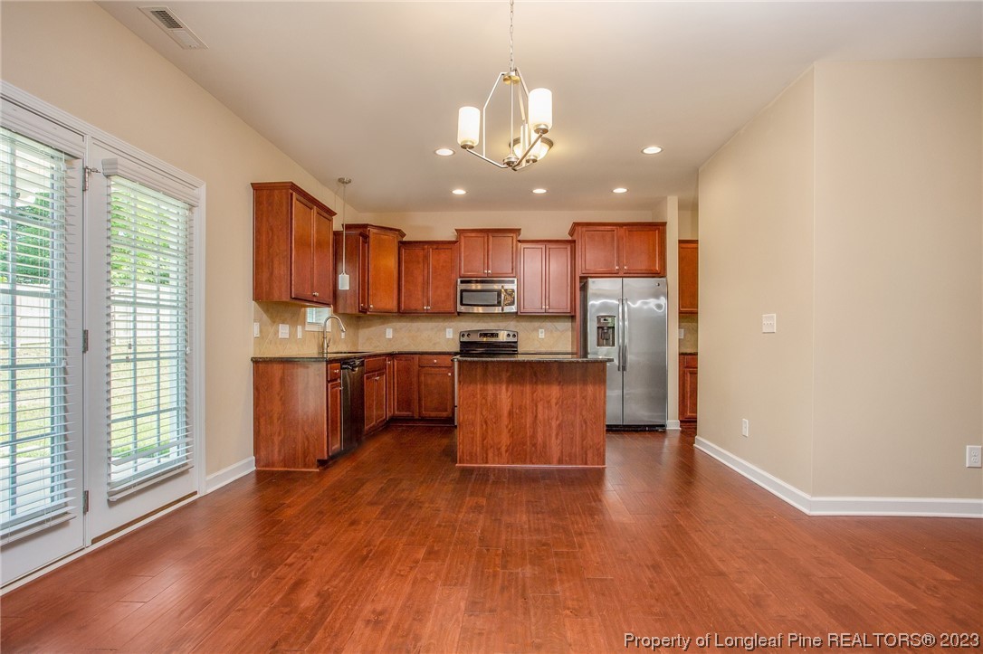 157 Shellbark Drive Spring Lake, NC 28390 - Photo 9 of 28 a kitchen with kitchen island granite countertop wooden floors stainless steel appliances a sink and a window