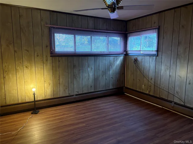 an empty room with wooden floor and windows with curtains