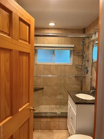 a bathroom with a granite countertop sink a toilet and shower