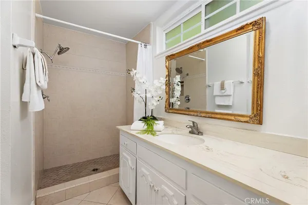 a bathroom with a granite countertop sink a mirror a vanity and shower