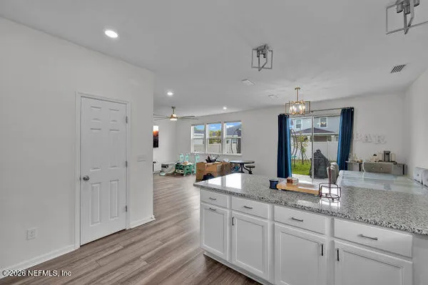 a kitchen with stainless steel appliances granite countertop a stove top oven a sink dishwasher a dining table and chairs with wooden floor