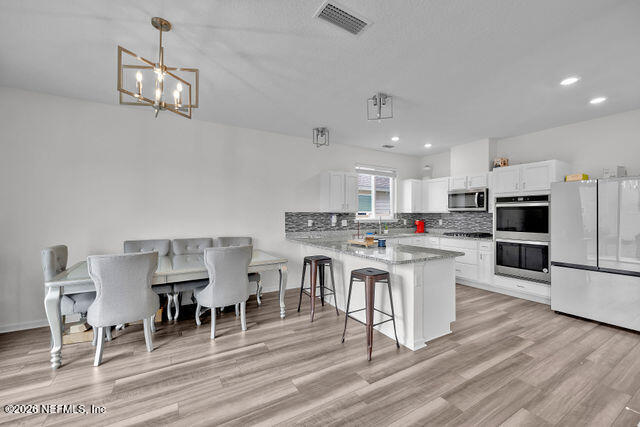 136 Peace River Road St. Johns, FL 32259 - Photo 15 of 40 a kitchen with stainless steel appliances granite countertop a stove top oven a sink dishwasher a dining table and chairs with wooden floor