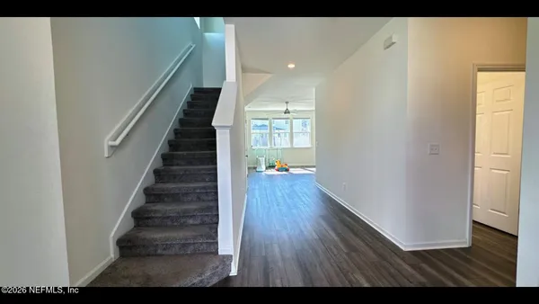 an empty room with wooden floor chandelier and windows