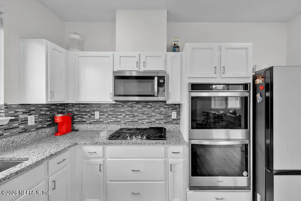 a kitchen with microwave a stove and cabinets