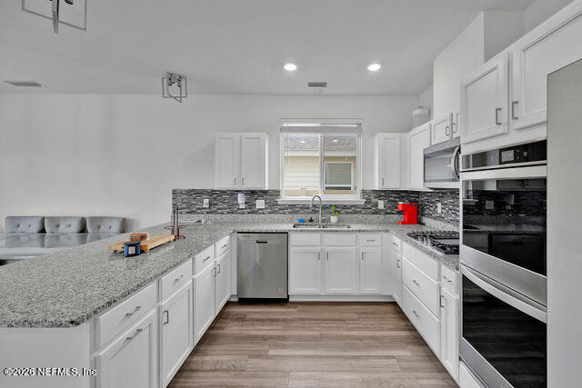 136 Peace River Road St. Johns, FL 32259 - Photo 9 of 40 a kitchen with granite countertop sink stainless steel appliances and white cabinets