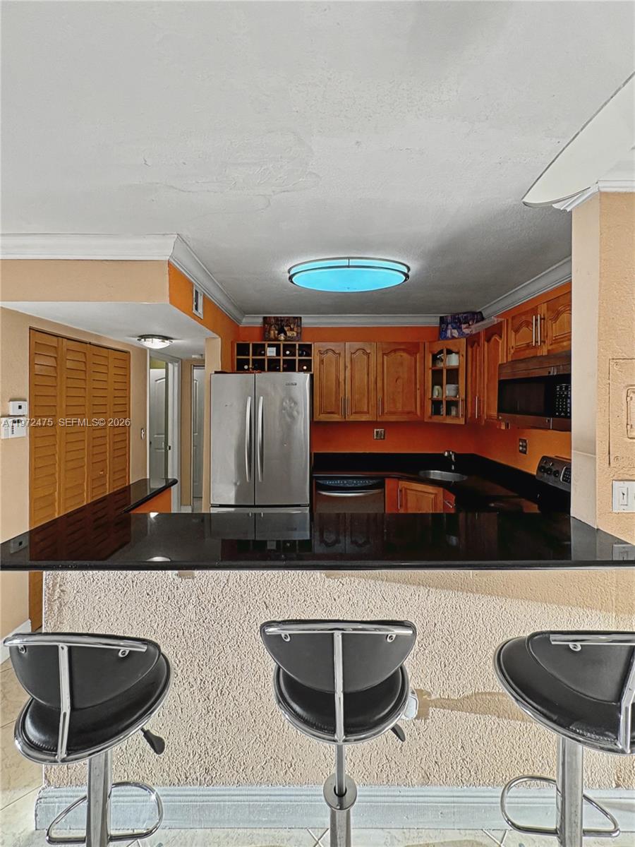 9417 Southwest 76th Street, Unit X36 Miami, FL 33173 - Photo 5 of 10 a kitchen with stainless steel appliances kitchen island granite countertop a table and chairs in it
