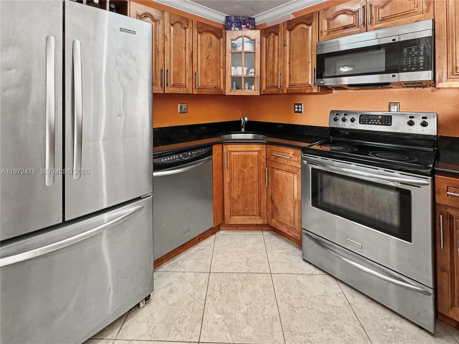 9417 Southwest 76th Street, Unit X36 Miami, FL 33173 - Photo 6 of 10 a kitchen with granite countertop a refrigerator stove and microwave