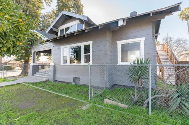 a view of a yard in front of a house with large windows