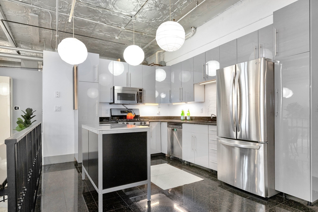 10 Williams Street, Unit 13 Boston, MA 02119 - Photo 16 of 38 a kitchen with stainless steel appliances granite countertop a refrigerator a stove and a sink