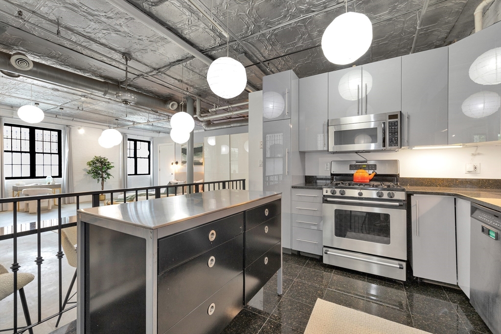 10 Williams Street, Unit 13 Boston, MA 02119 - Photo 21 of 38 a kitchen with stainless steel appliances granite countertop a sink a stove and a wooden floors