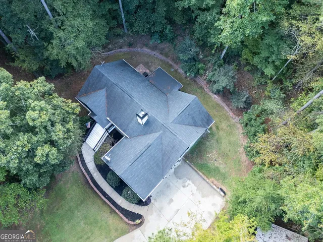 an aerial view of a house with outdoor space and trees all around