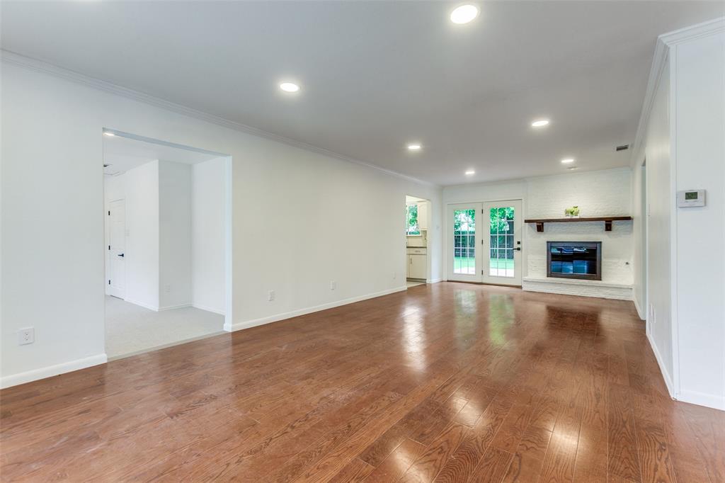 2718 Runningbrook Lane Dallas, TX 75228 - Photo 13 of 28 an empty room with wooden floor fireplace and windows