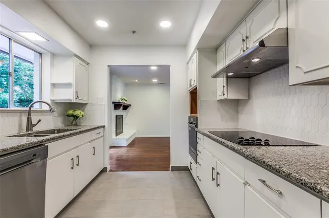 a large kitchen with stainless steel appliances a sink a stove and cabinets