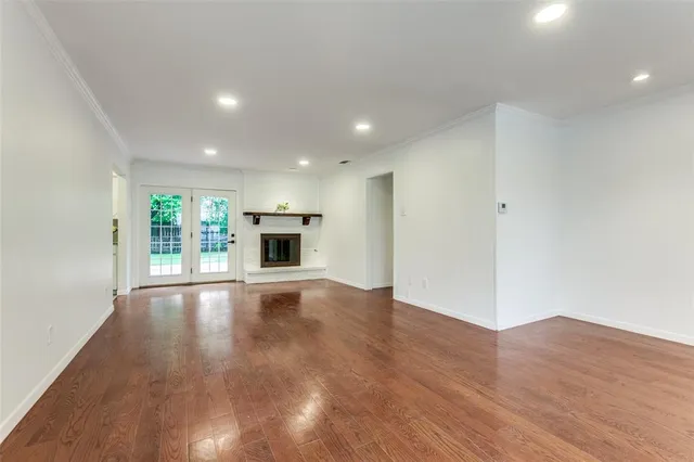 an empty room with wooden floor fireplace and windows