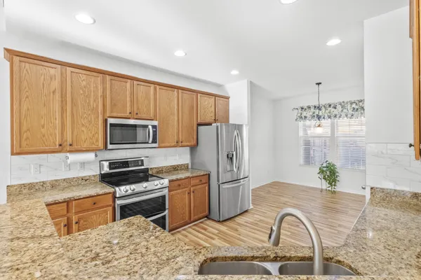a large kitchen with stainless steel appliances granite countertop a lot of counter space and wooden floors