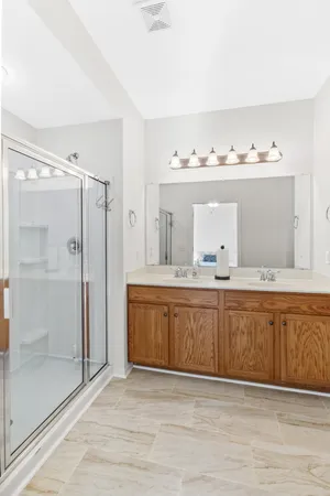 a bathroom with a double vanity sink mirror and shower