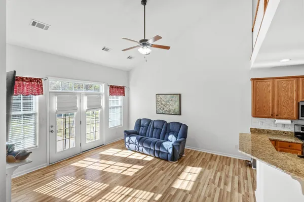 a living room with furniture kitchen view and a wooden floor
