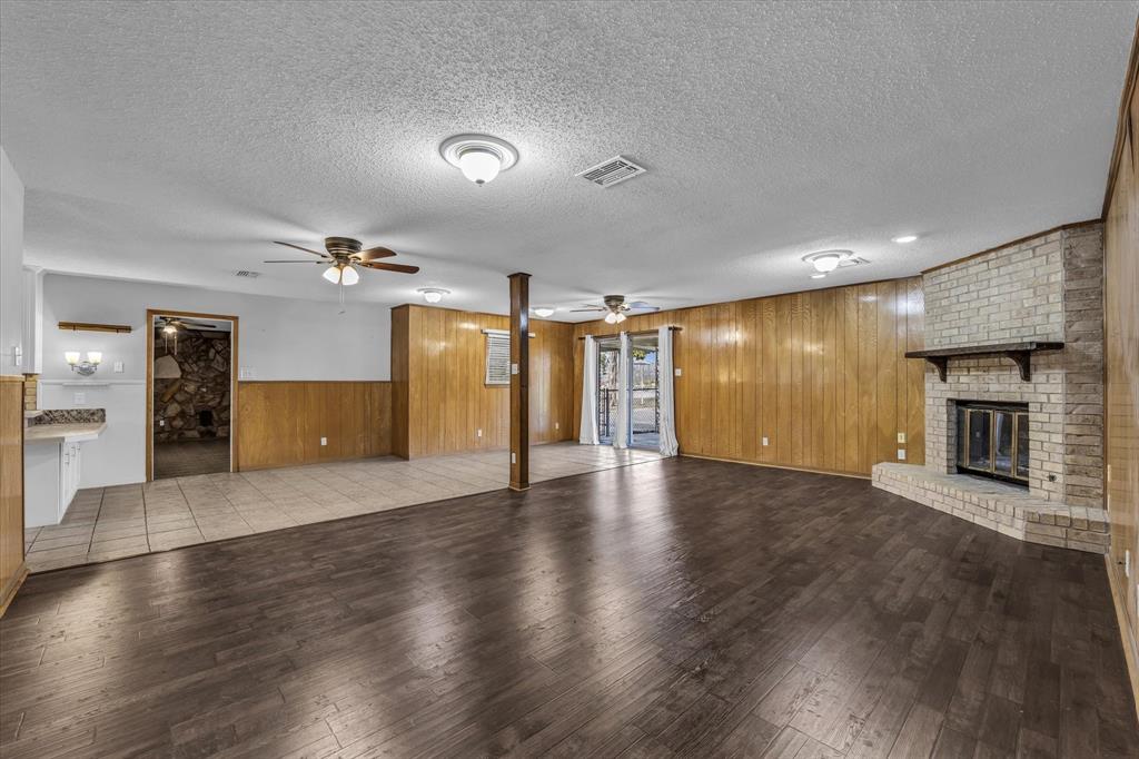 4325 Shady Glen Drive Waco, TX 76708 - Photo 4 of 40 an empty room with wooden floor fireplace and kitchen view