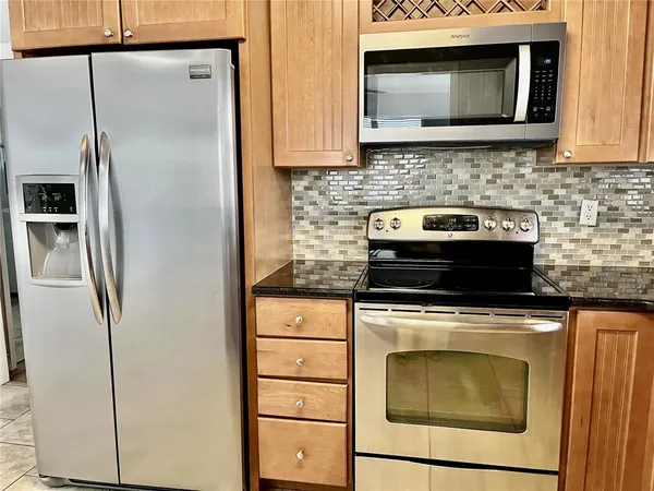a kitchen with stainless steel appliances granite countertop a stove microwave and refrigerator