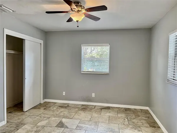 an empty room with windows and fan