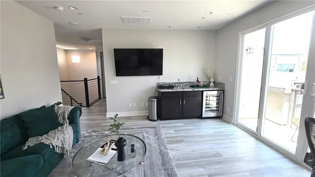 a living room with furniture a flat screen tv and a refrigerator