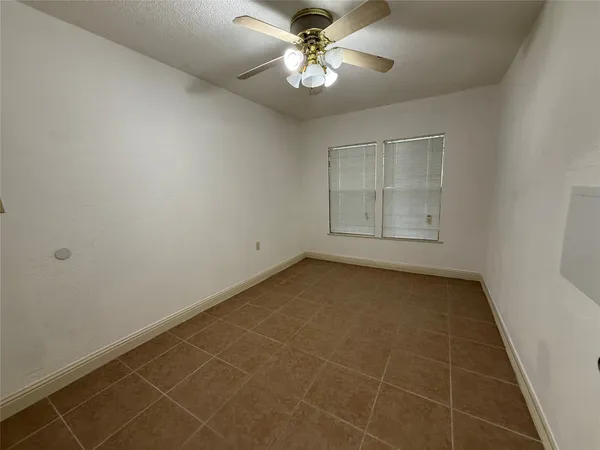 an empty room with a ceiling fan and a window