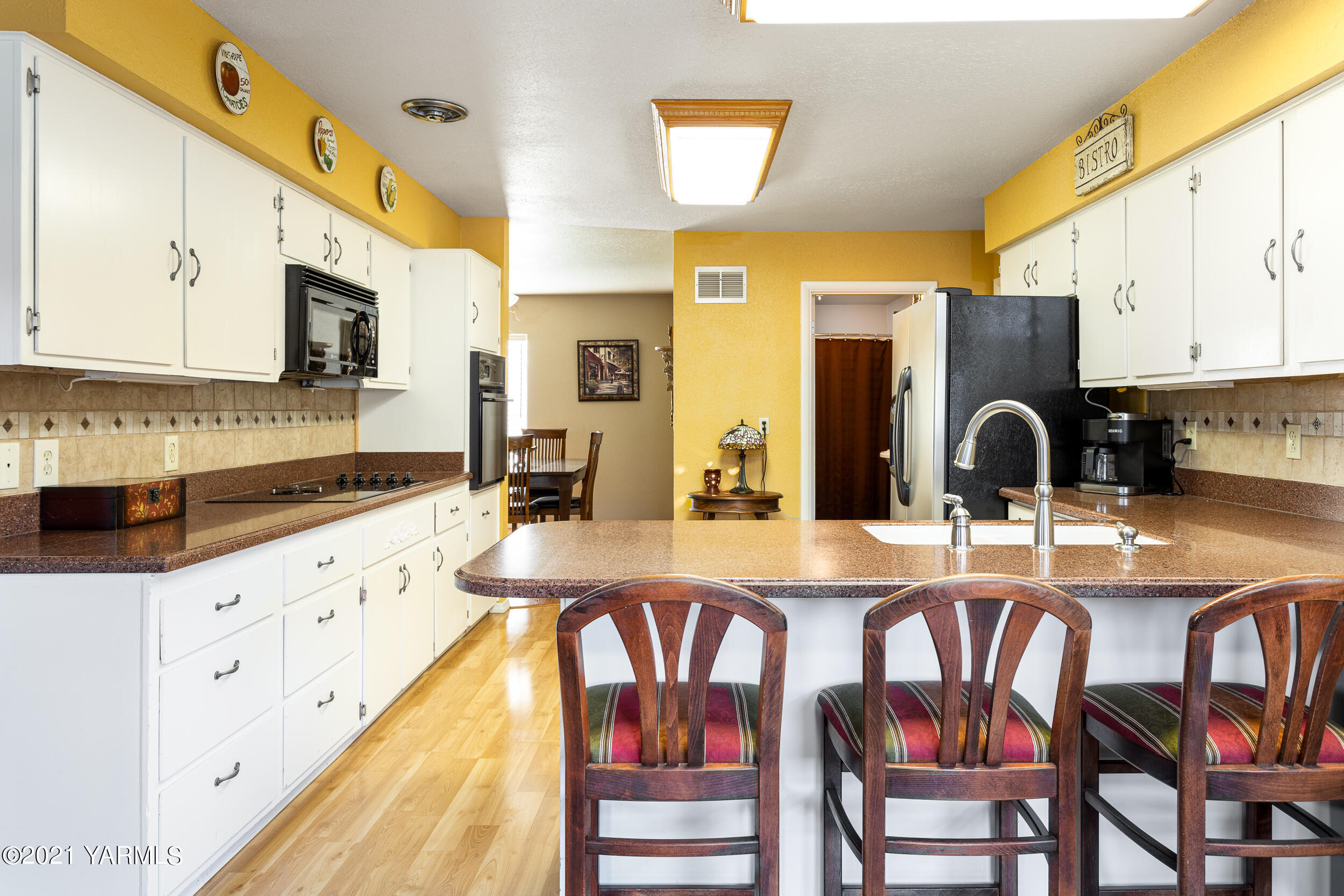 550 McPhee Road Naches, WA 98937 - Photo 11 of 28 a kitchen with stainless steel appliances granite countertop a stove top oven a sink a dining table and chairs with white cabinets