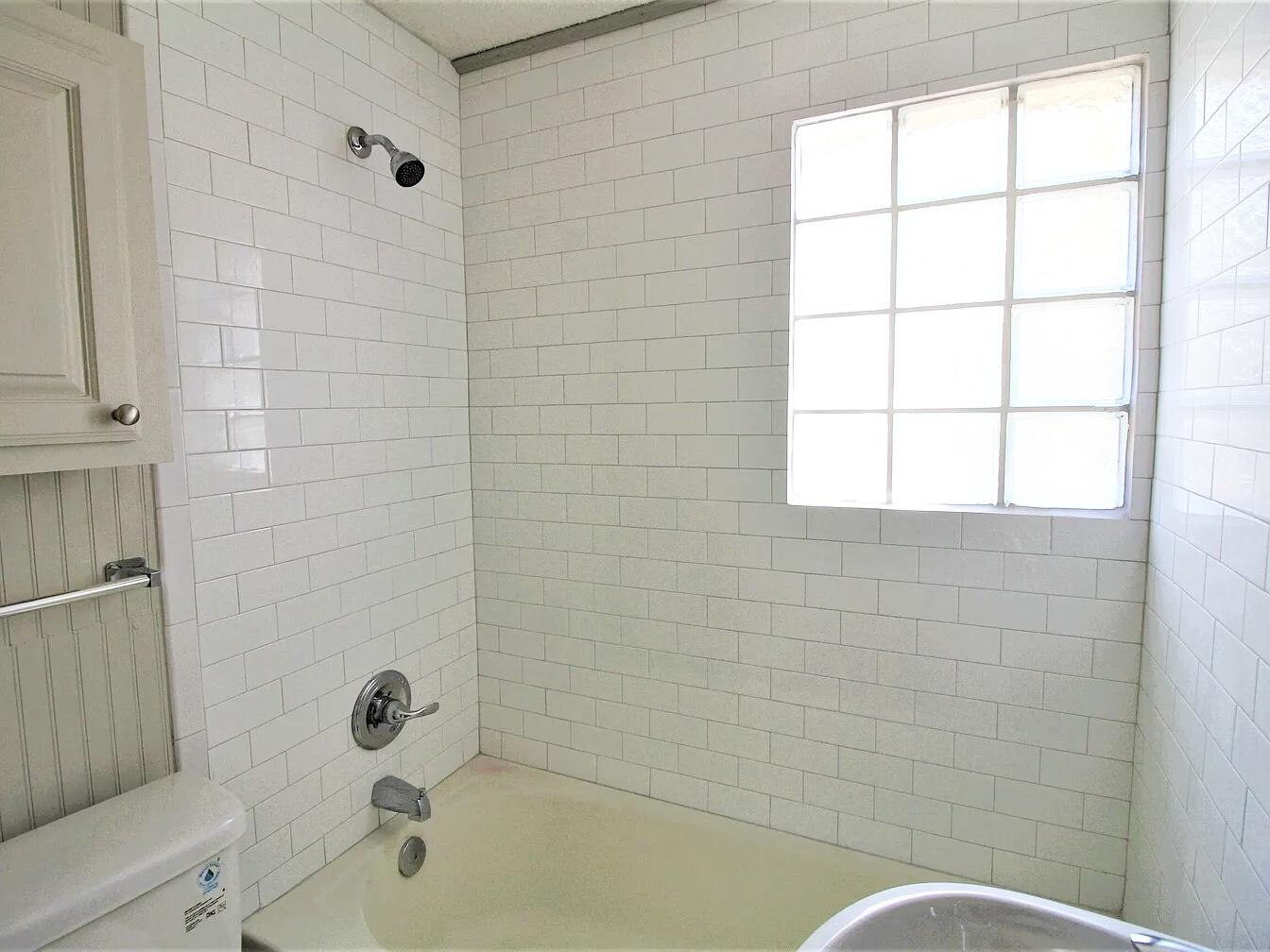 2216 30th Street, Unit REAR Lubbock, TX 79411 - Photo 12 of 14 a bathroom with a bathtub and window