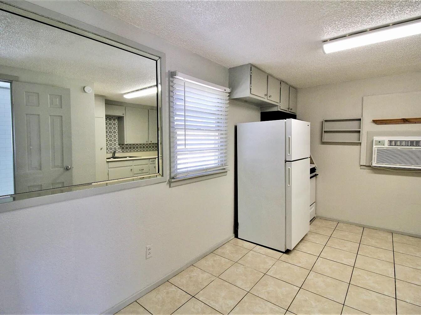 2216 30th Street, Unit REAR Lubbock, TX 79411 - Photo 9 of 14 a view of a refrigerator in kitchen and an empty room in wooden floor