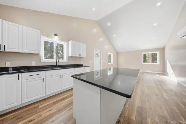 a kitchen with stainless steel appliances granite countertop a sink dishwasher a stove and white countertops with wooden floor