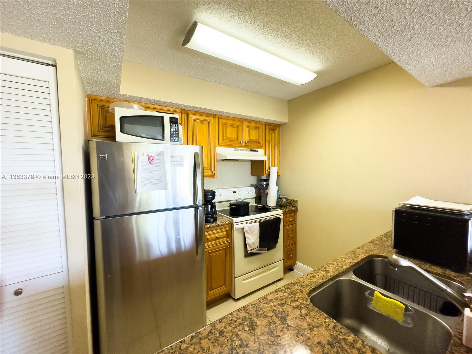 5654 Rock Island Road, Unit 234 Tamarac, FL 33319 - Photo 4 of 10 a white refrigerator freezer and a stove sitting inside of a kitchen
