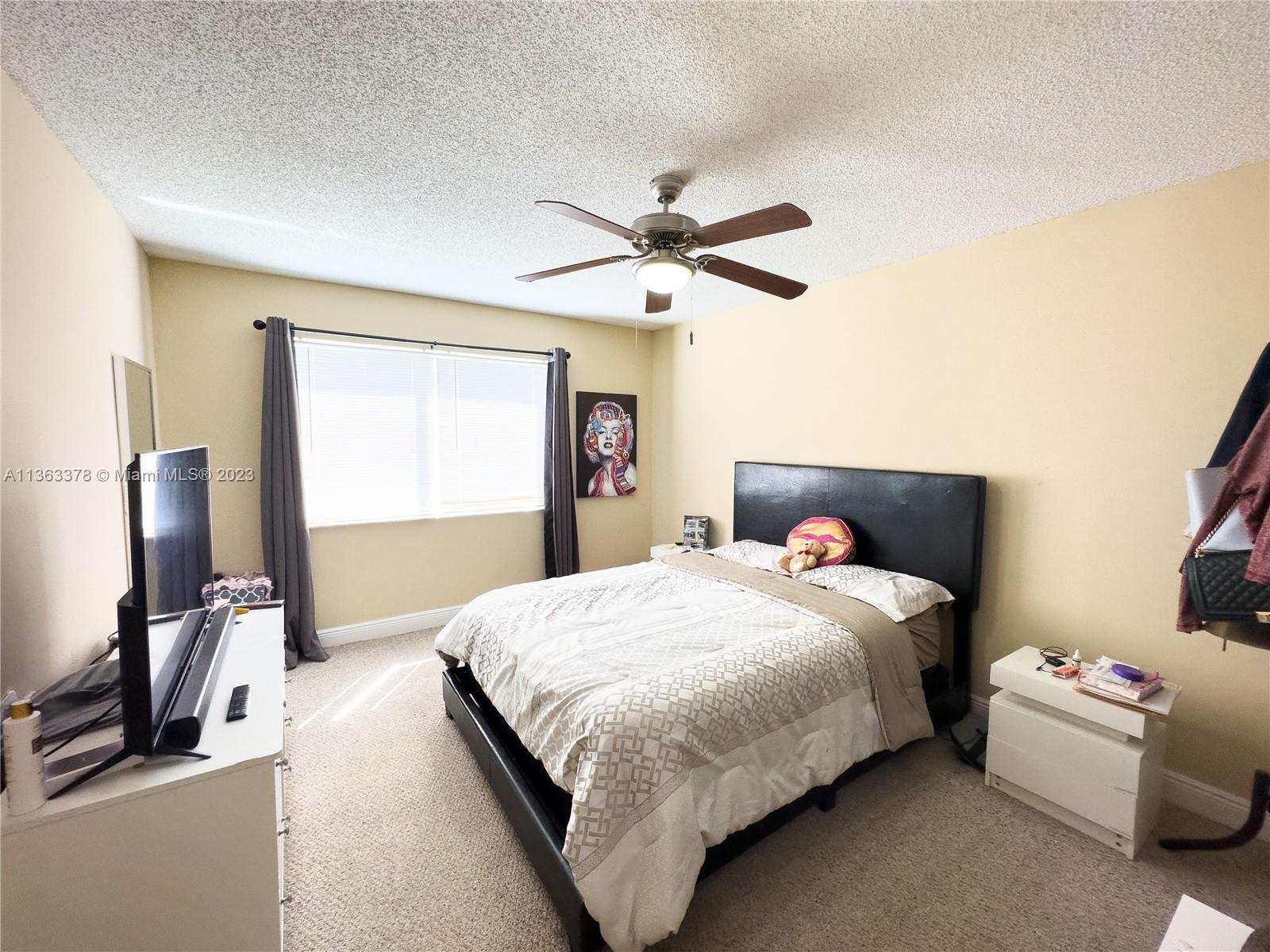 5654 Rock Island Road, Unit 234 Tamarac, FL 33319 - Photo 5 of 10 a bedroom with a bed and a chandelier