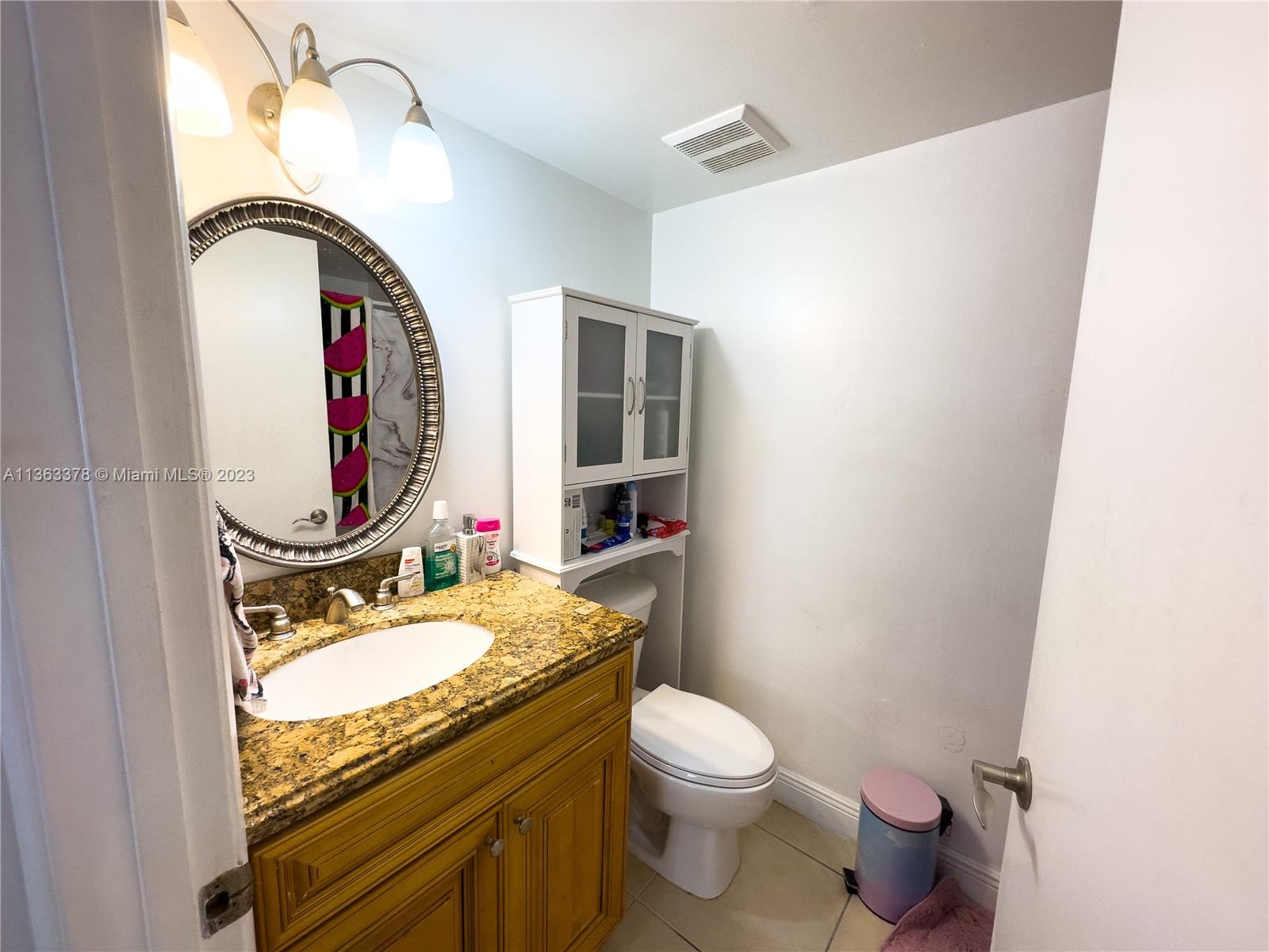 5654 Rock Island Road, Unit 234 Tamarac, FL 33319 - Photo 8 of 10 a bathroom with a granite countertop toilet a sink and a mirror