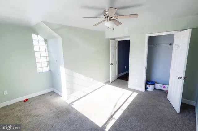 a view of an empty room with closet and a window