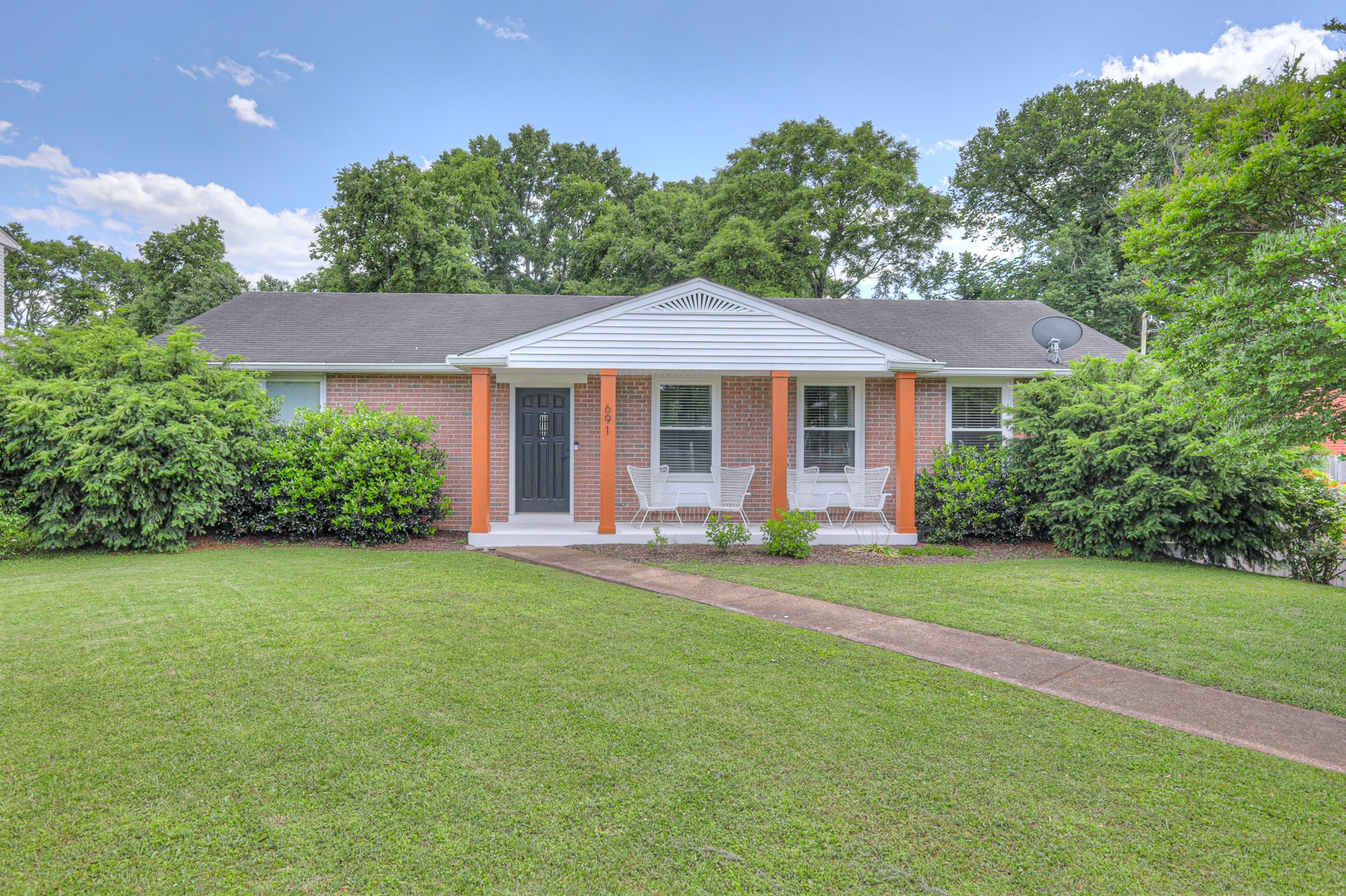 a front view of a house with a yard and trees