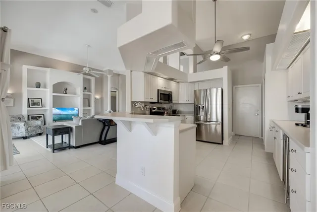 a kitchen with stainless steel appliances kitchen island granite countertop a refrigerator oven a sink dishwasher and white cabinets with wooden floor