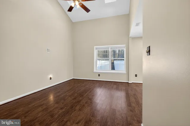 an empty room with wooden floor cabinet and windows