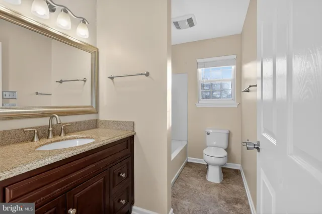 a bathroom with a granite countertop sink a toilet and a mirror