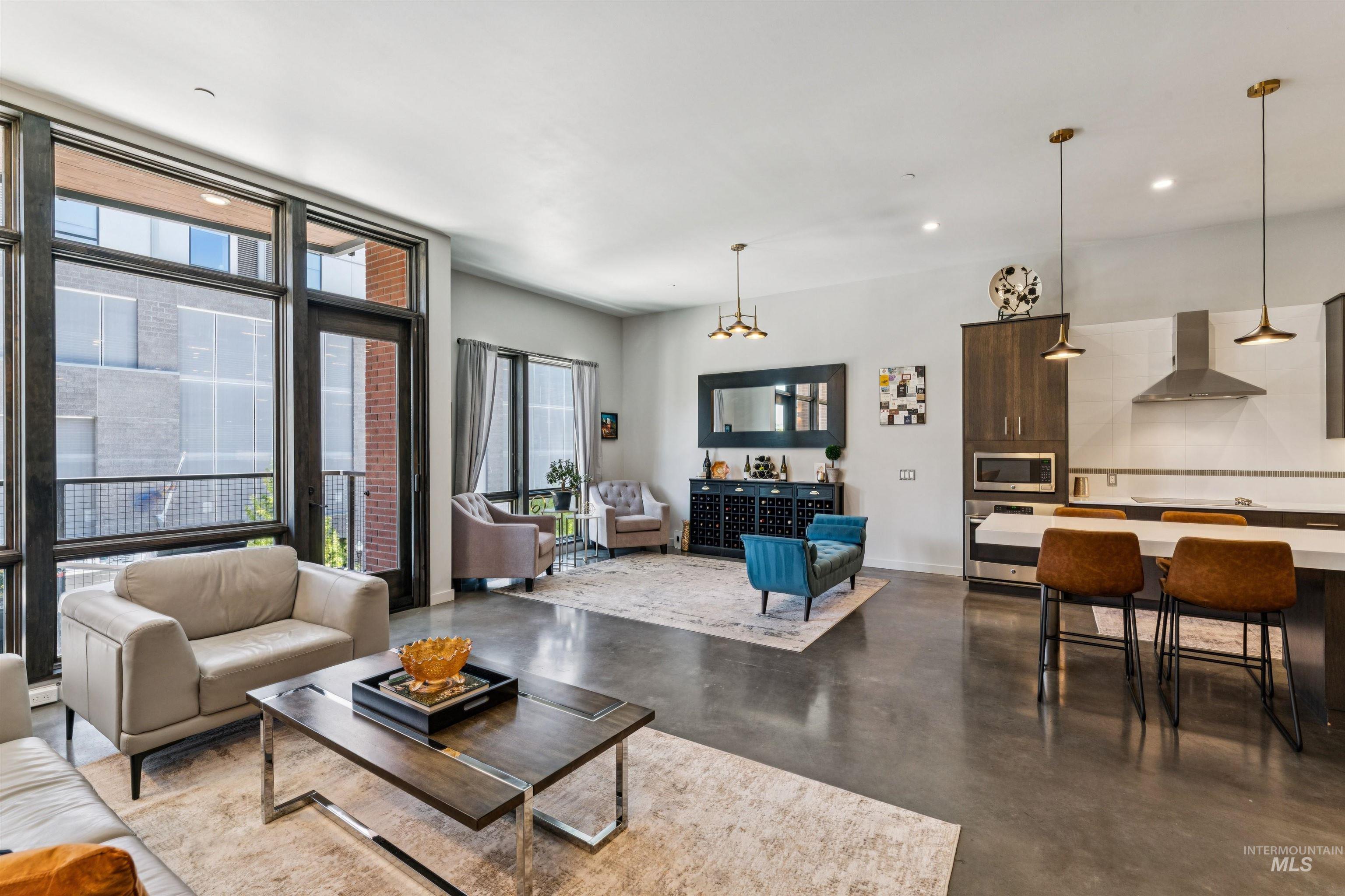 119 South 10th Street, Unit 307 Boise, ID 83702 - Photo 9 of 47 Open-concept living space featuring high ceilings, large floor-to-ceiling windows, polished concrete flooring, a modern kitchen island with seating, and stainless steel appliances