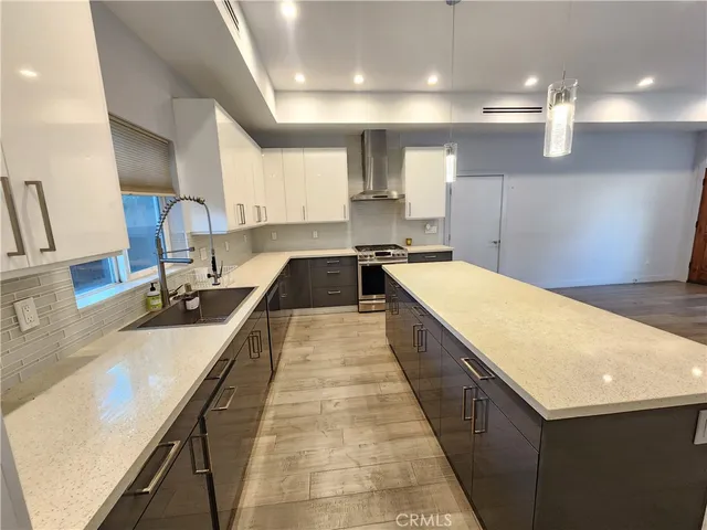 a large kitchen with kitchen island a large counter space a sink a stove and a wooden floors